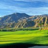 A sunny view of a green with mountains in background at Clive Clark Course from Hideaway Club